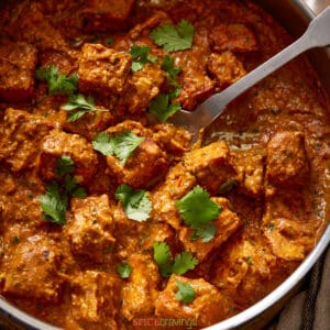 tikka masala with tofu in white speckled bowl with spoon