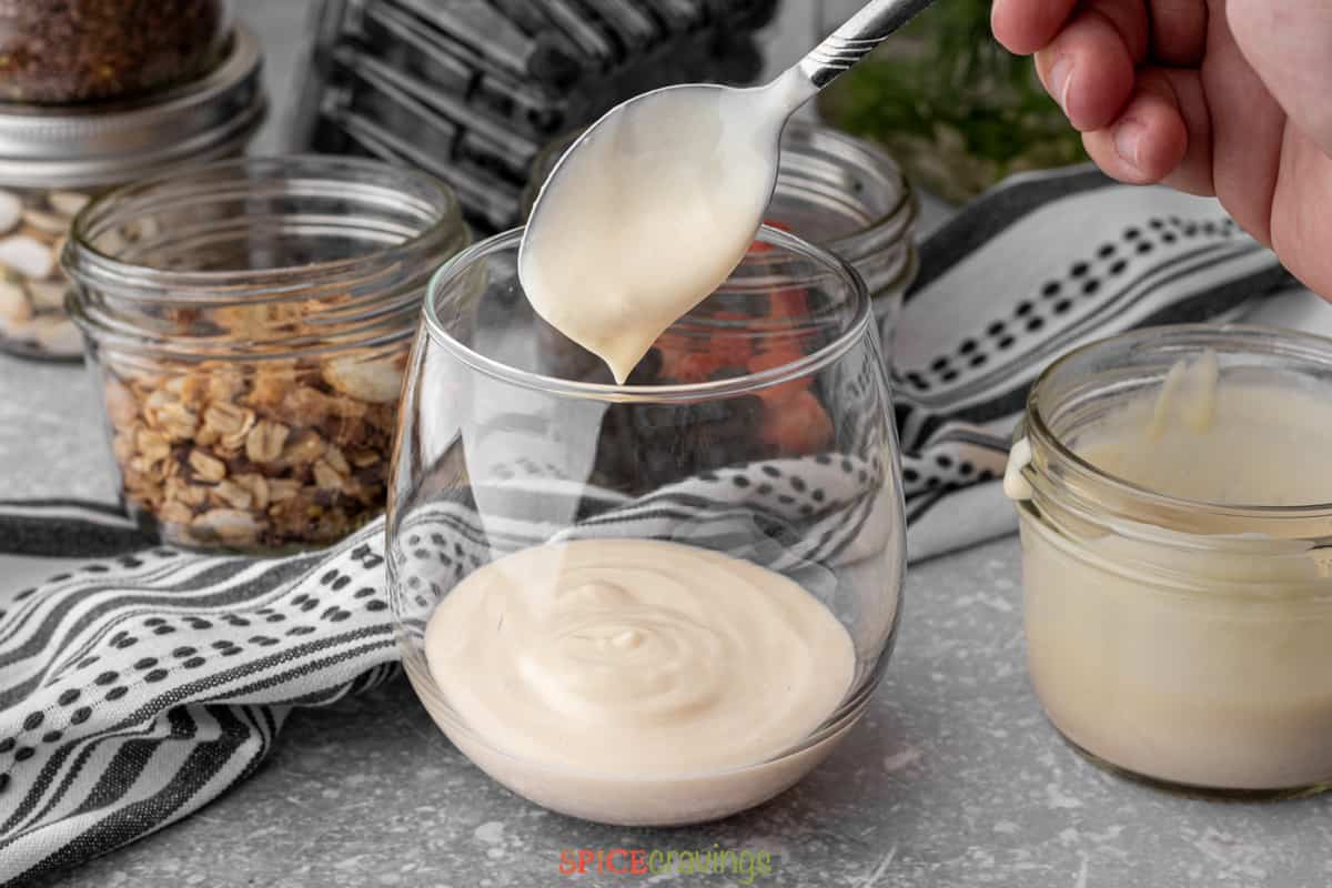 spooning yogurt into glass jar