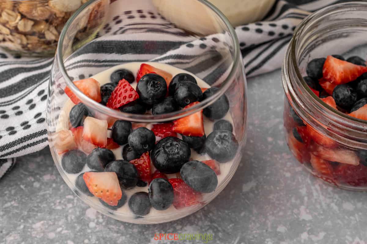berries on top of Greek yogurt in glass jar