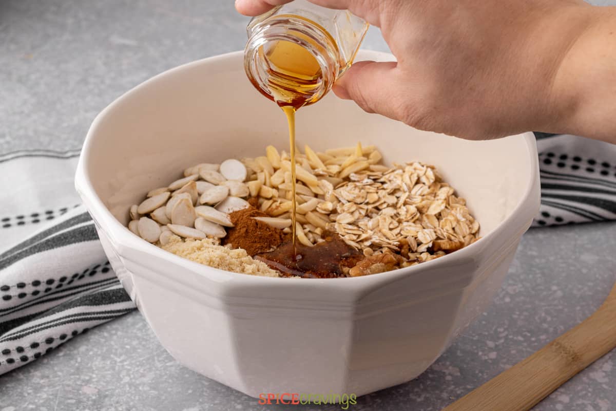 woman pouring maple syrup over protein granola ingredients