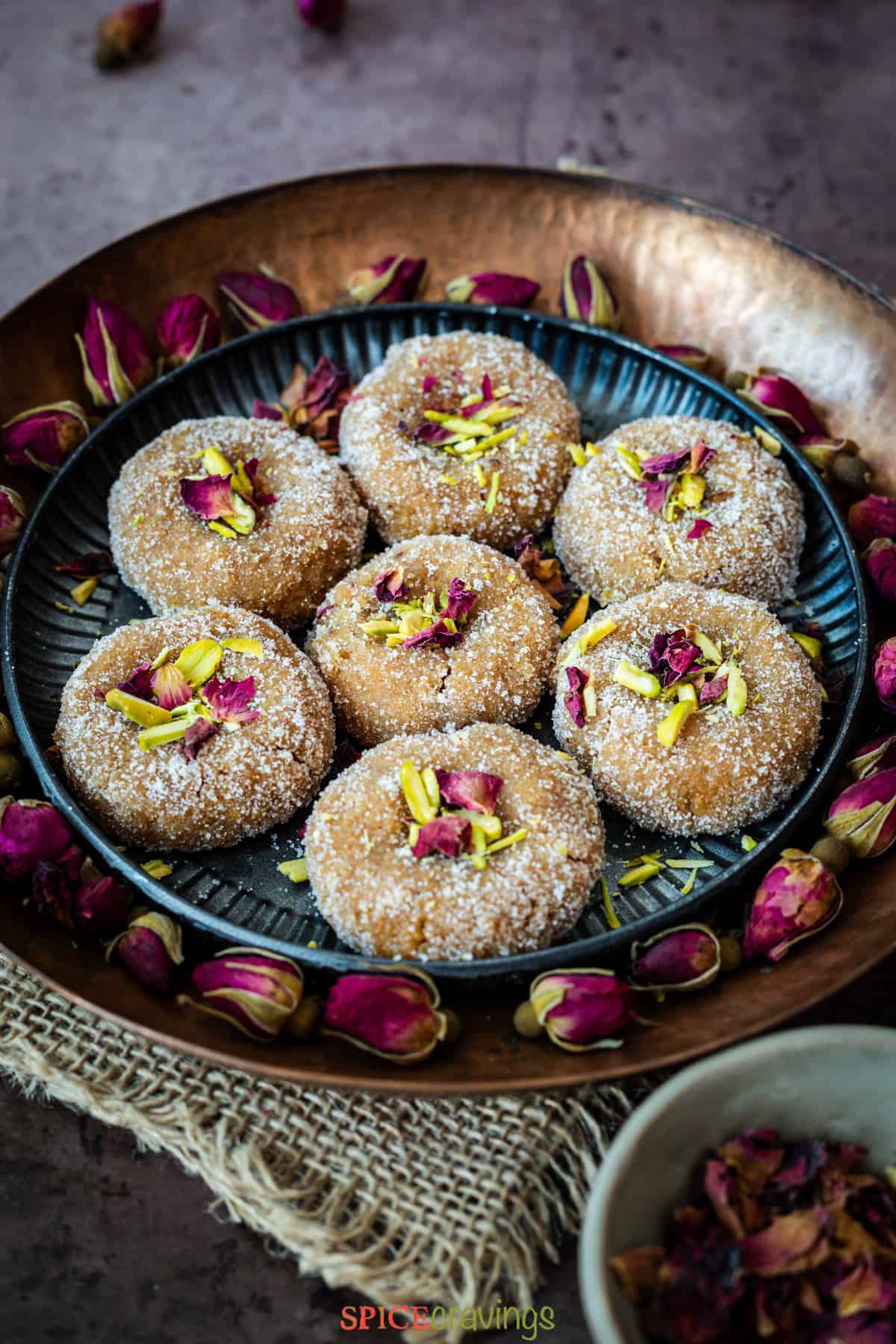 Indian sweet called peda on metal plate decorated with dried rose buds