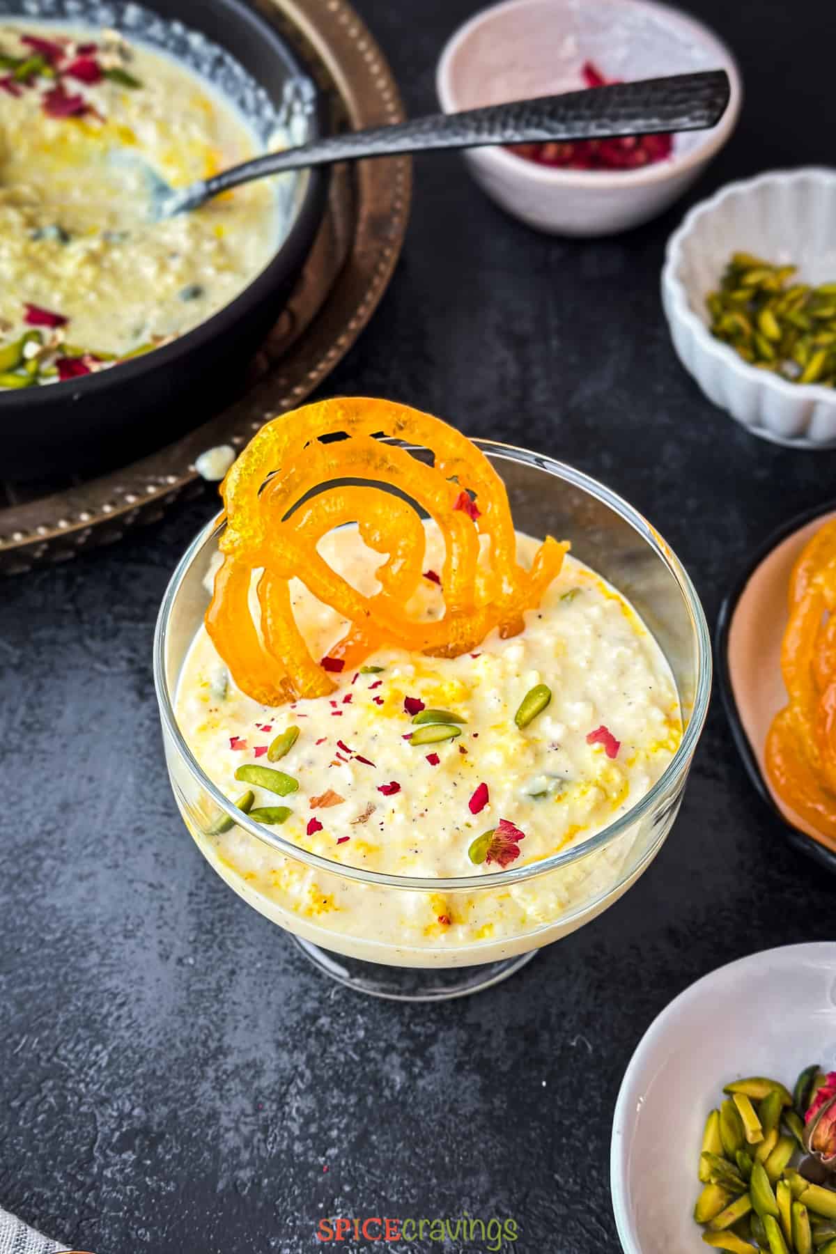 Dessert cup filled with Indian rabdi, garnished with rose, nuts and jalebi