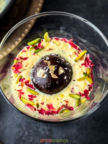 Rabdi cup topped with gulab jamun garnished with pistachios and rose