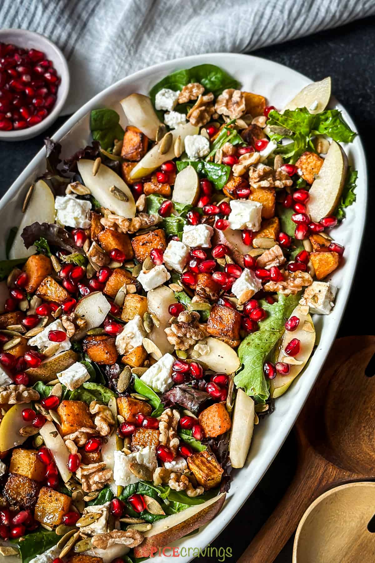 White platter of butternut squash salad with feta cheese and pomegranate