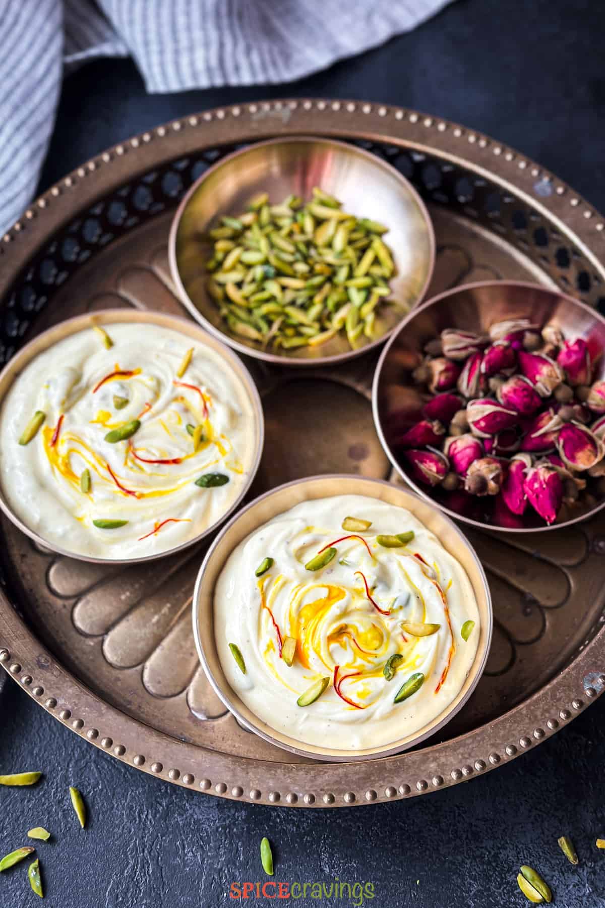 4 copper bowls, 2 with shrikhand, 1 with rose buds, and the 4th with sliced pistachios