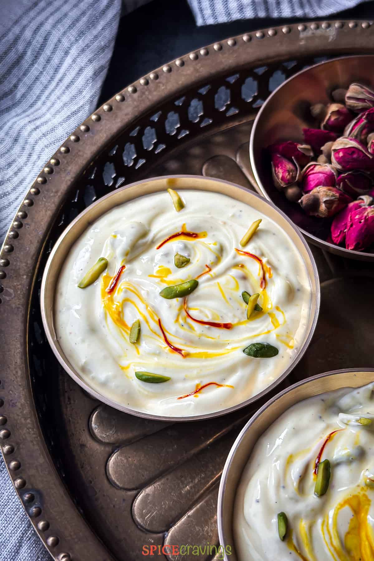 Shrikhand served in copper bowl garnished with saffron and pistachio