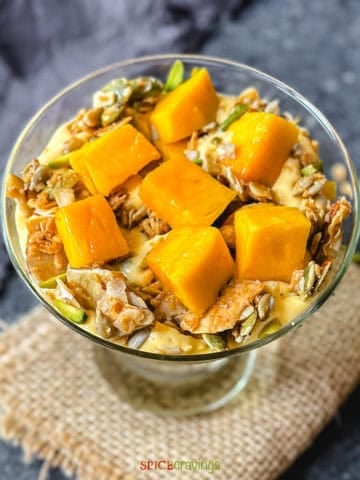 cubed mango, granola, pistachios, and yogurt in a martini glass