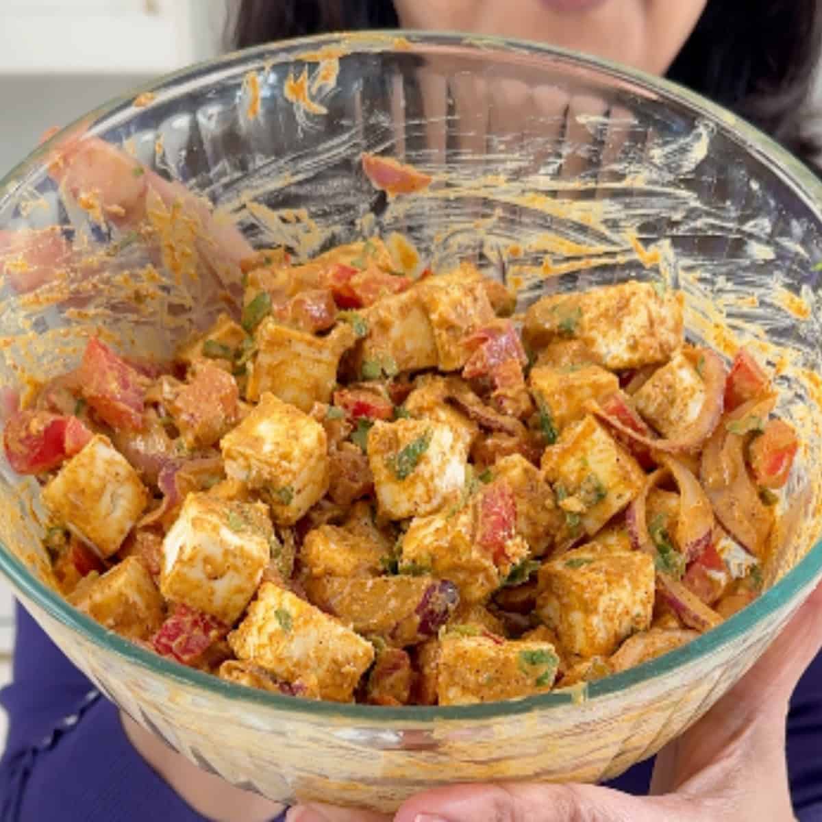 mixing paneer and veggies in a tandoori marinade