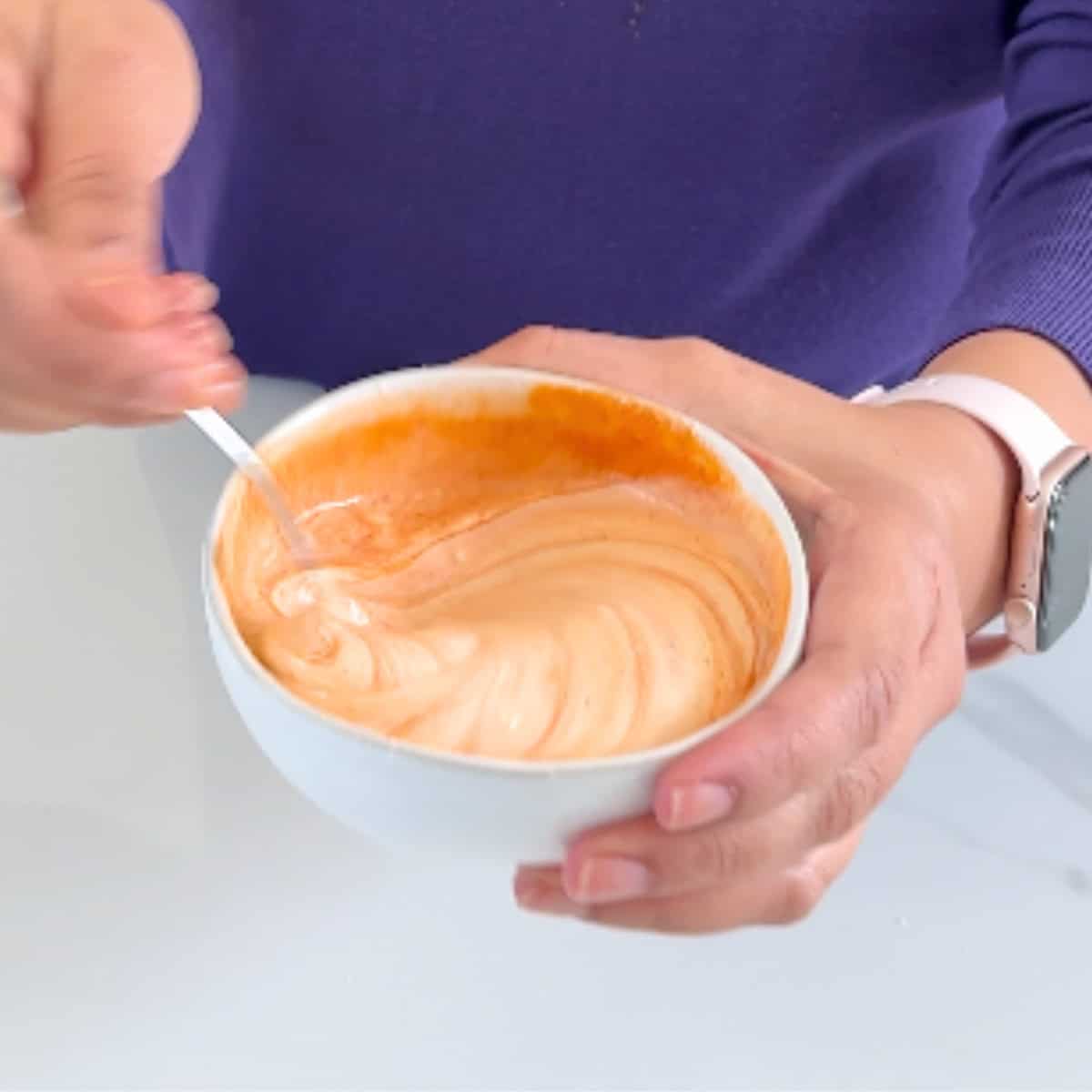 Making sriracha mayo in a white bowl