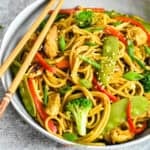 Instant Pot chicken lo mein with chicken, cabbage, carrots, and peppers, garnished with scallions and sesame seeds