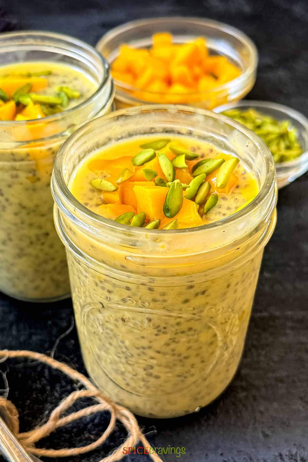 mango chia pudding topped with pistachio and chopped mango in a glass jar