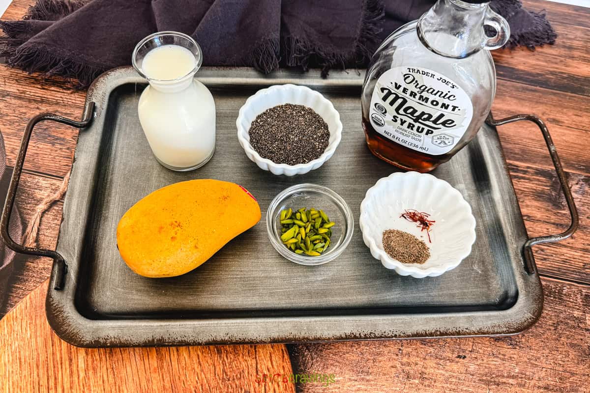 Ingredients for making Indian-inspired mango chia pudding including mango, milk, chia seeds, pistachios, cardamom and saffron.