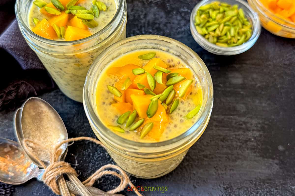 top view of a glass jar of chia and mango pudding topped with chopped mango and pistachio
