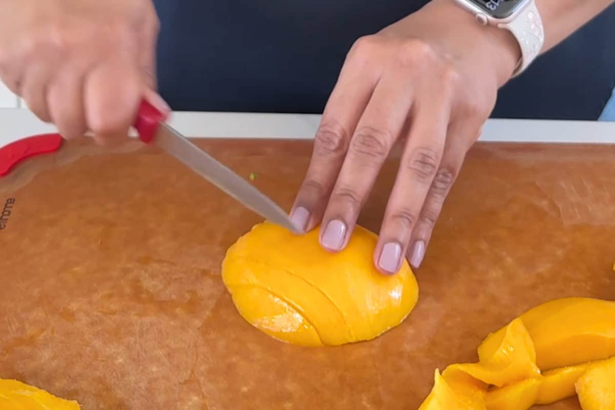 slicing mango on a cutting board to make mango pudding with chia seeds