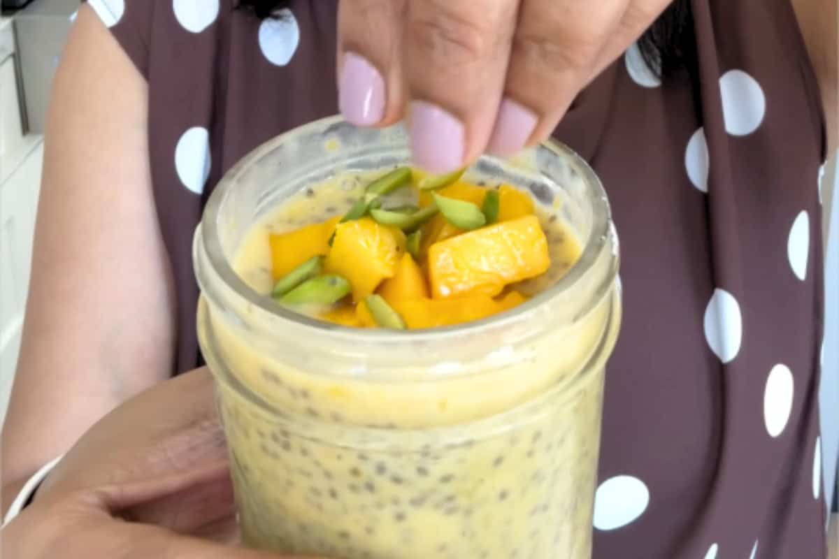 garnishing a mango chia pudding jar with chopped mango and pistachio