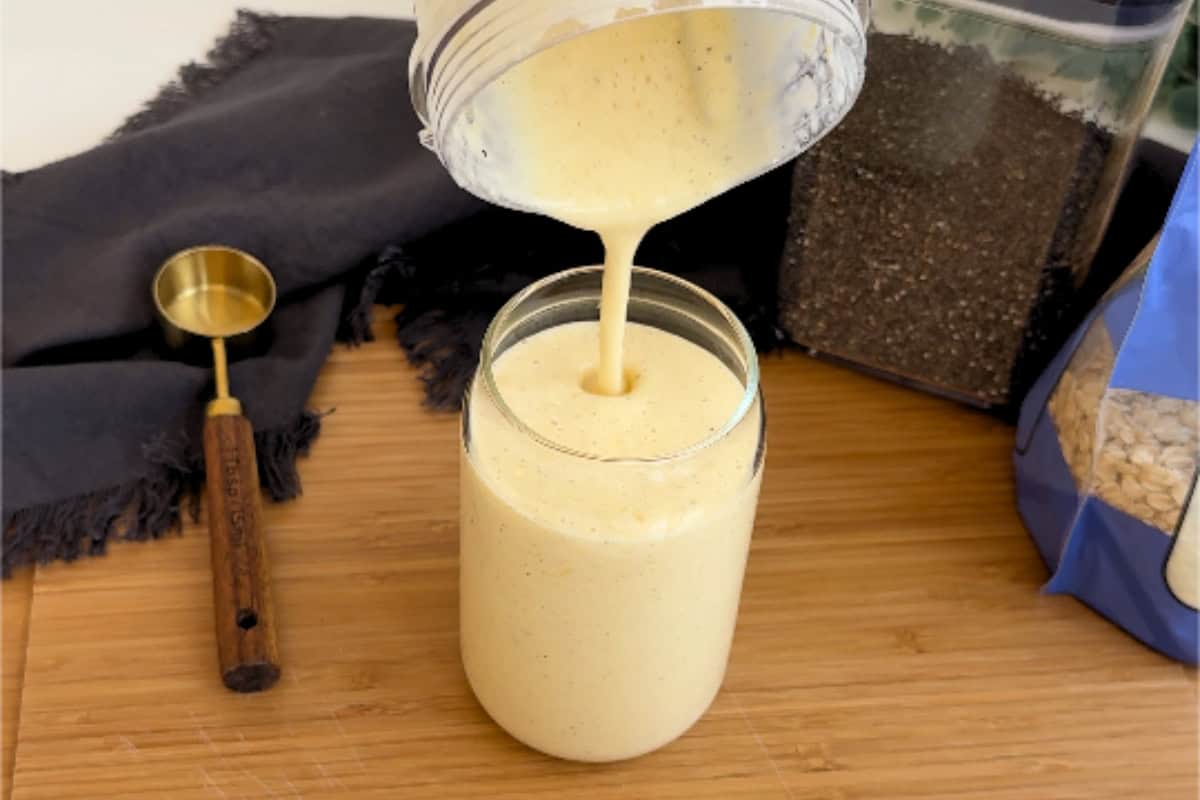 Pouring mango lassi mix into a jar for making mango overnight oats with chia seeds