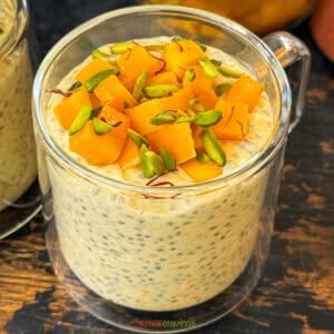 cup of mango overnight oats with chia seeds topped with chopped mango and pistachios