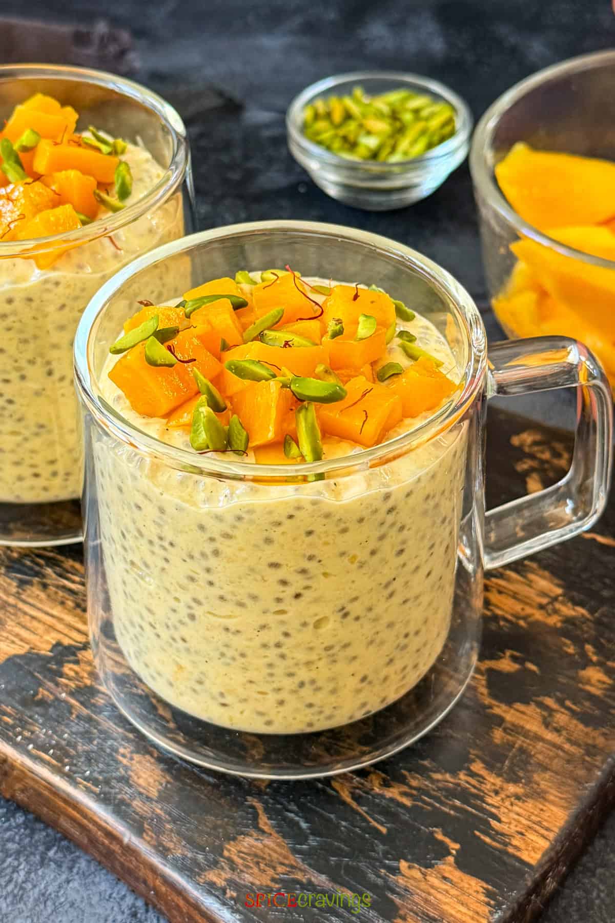 cup of mango overnight oats with chia seeds topped with chopped mango and pistachios