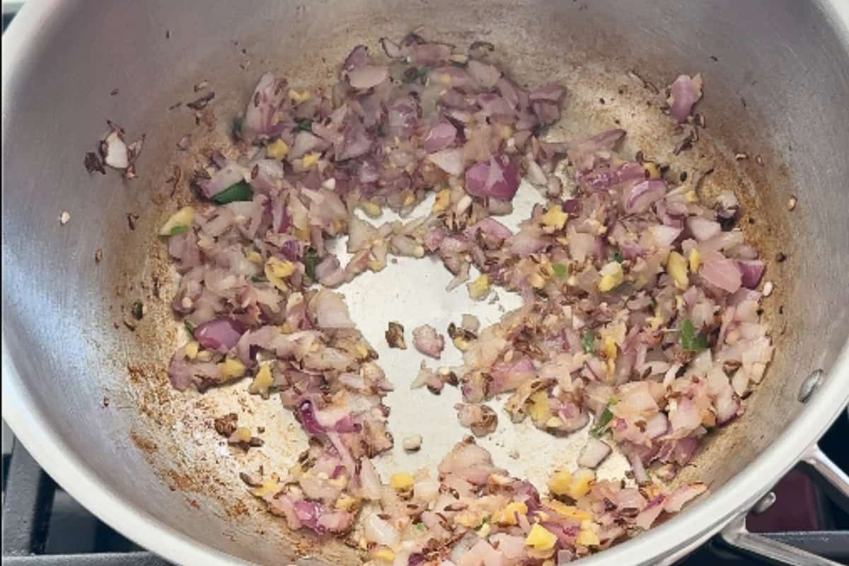 onions, ginger and garlic being sauteed in a pan